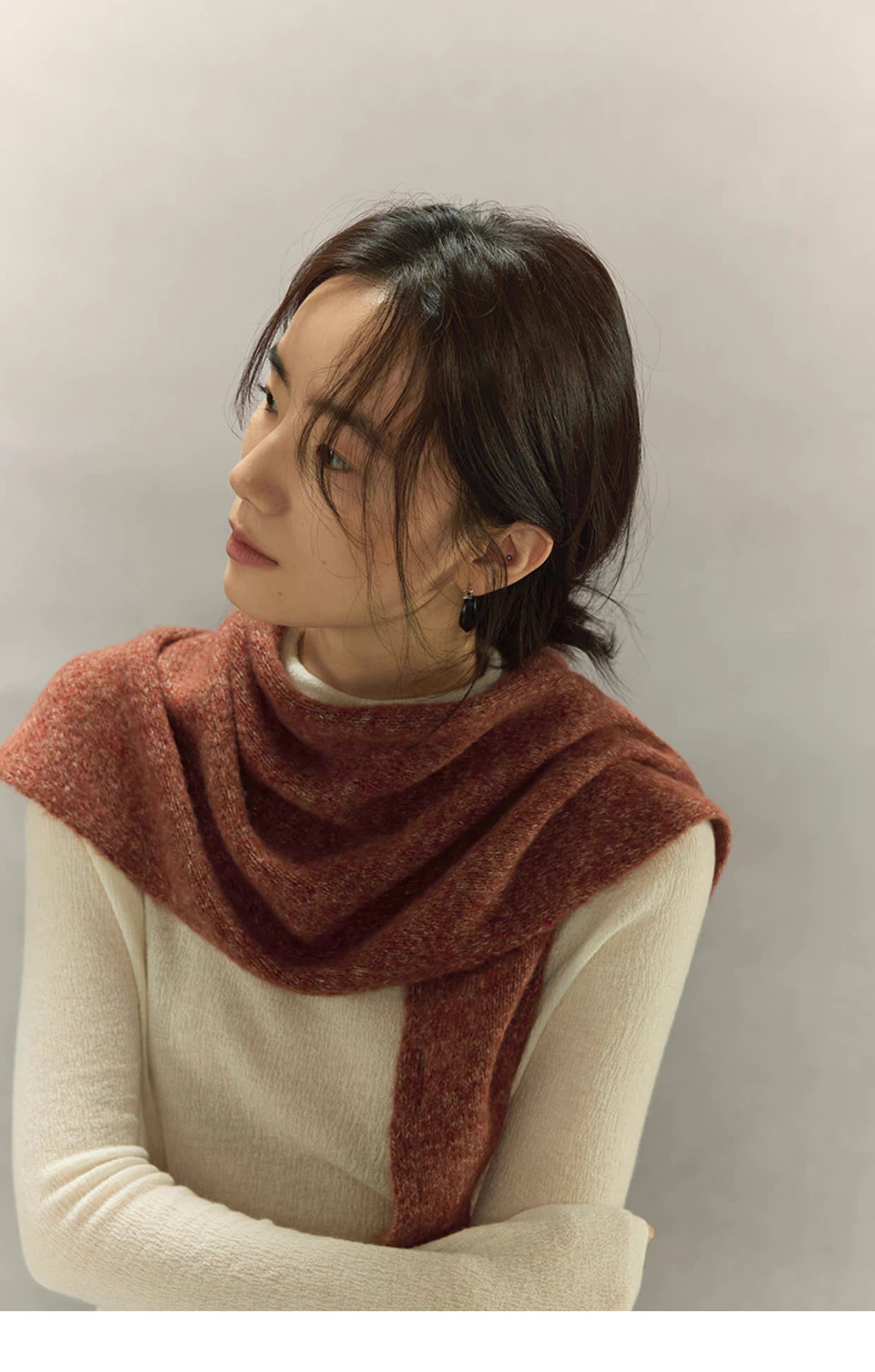 woman looking upward while wearing rust brown cashmere wool scarf