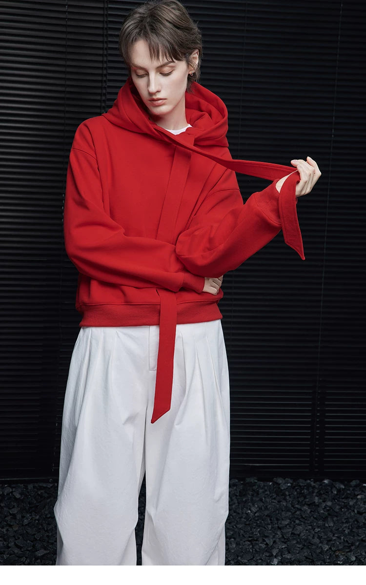 Model pulling the long self-tie ribbon of a Scarlet Red hooded sweatshirt, arms crossed
