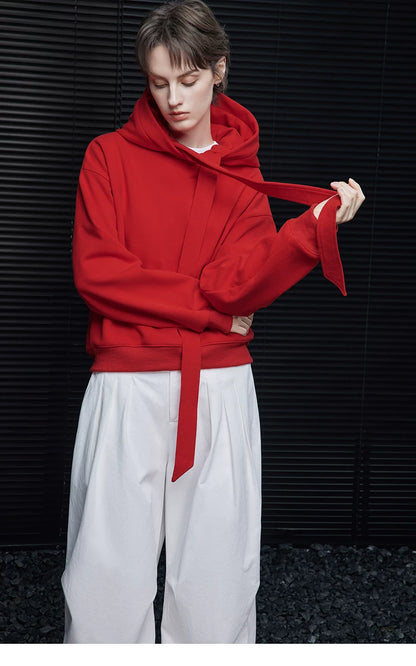 Model pulling the long self-tie ribbon of a Scarlet Red hooded sweatshirt, arms crossed
