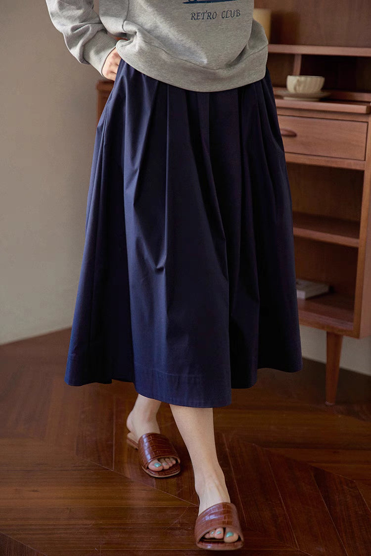 Close-up of The Sculptural Pleat A-Line Skirt in navy blue showing detailed pleats, smooth fabric texture and flowing A-line movement