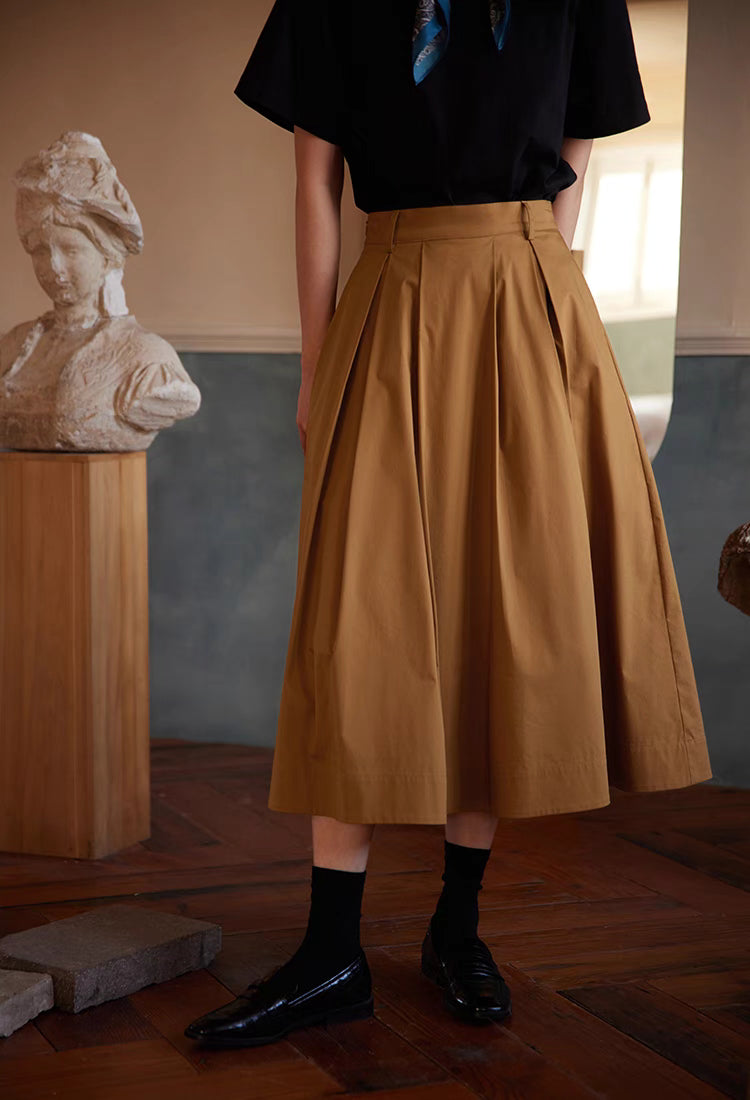 Front detail of The Sculptural Pleat A-Line Skirt in rattan yellow highlighting structured pleats, high waist fit and voluminous midi silhouette