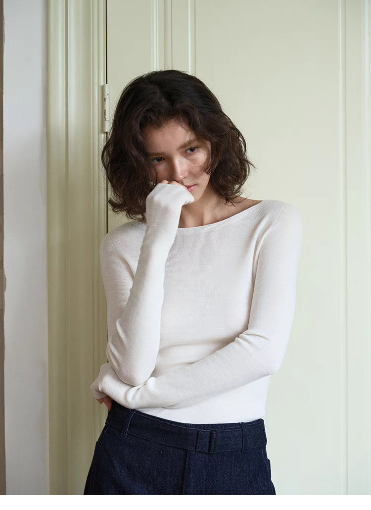 Model wearing vanilla white seamless sculpt merino sweater standing by door, showcasing slim fit and soft lightweight texture