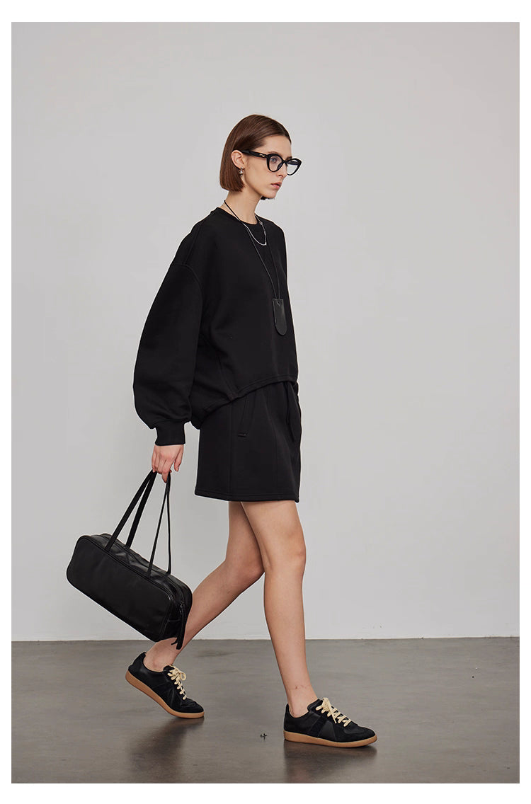 Side view of women’s oversized black sweatshirt with mini skirt casual loungewear