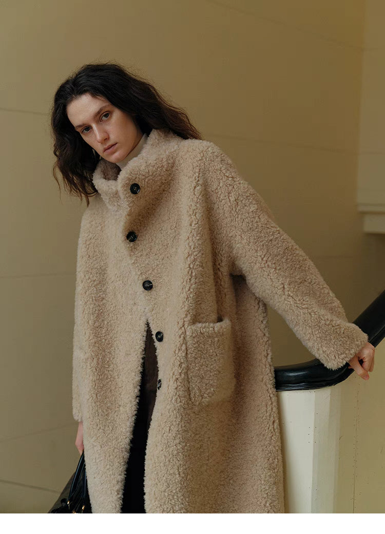 Model wearing Sierra Luxe Shearling Coat in beige apricot featuring stand collar, button closure, plush wool texture, and relaxed straight silhouette