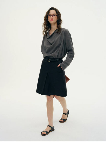 Woman wearing charcoal gray silk cowl neck top with black pleated skirt
