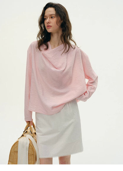 Woman wearing pink silk cowl neck top with light gray skirt, front view