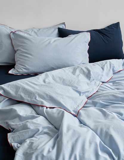 Light blue cotton pillows with red edge stitching from Skyline bedding set paired with navy blue flat sheet