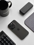 Clear black transparent phone case on iPhone placed on desk with keyboard mug and accessories lifestyle scene
