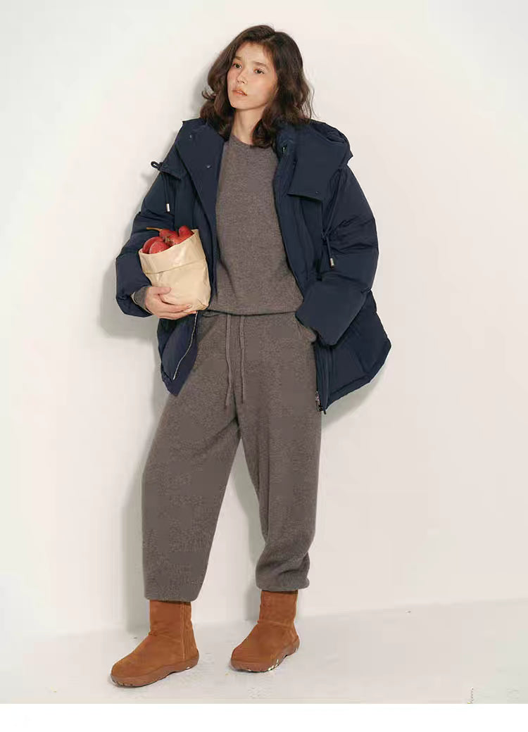 Full-body view of navy blue puffer jacket styled with knit top and skirt while the model stands indoors.