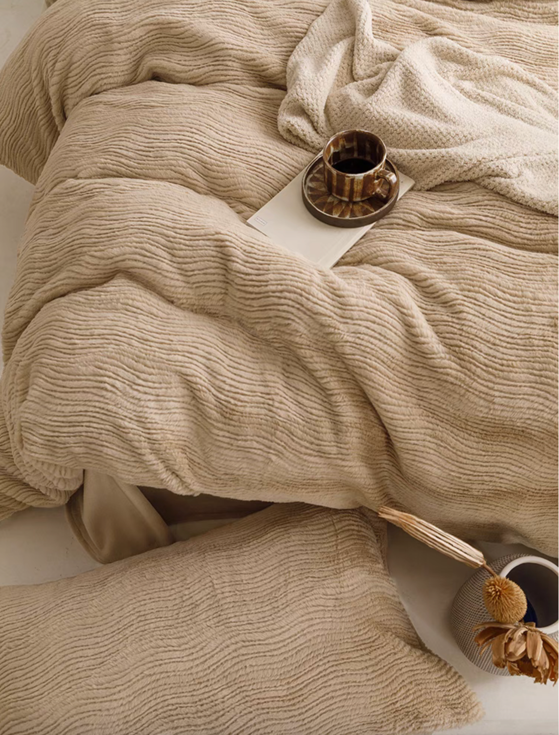Top view of SnowRabbit plush fur duvet cover and sheet set in coffee color showing textured bedding with cup and cozy blanket