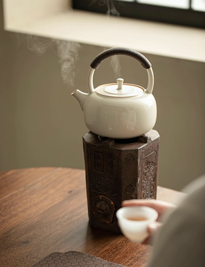Soda Glaze Ceramic Teapot in off-white placed on an electric ceramic stove with visible steam rising during heating