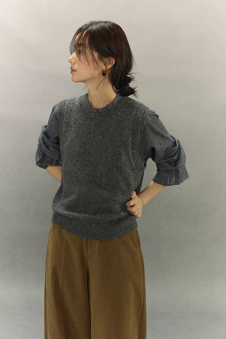 Side view of speckled wool-blend vest with rolled sleeves and relaxed silhouette.
