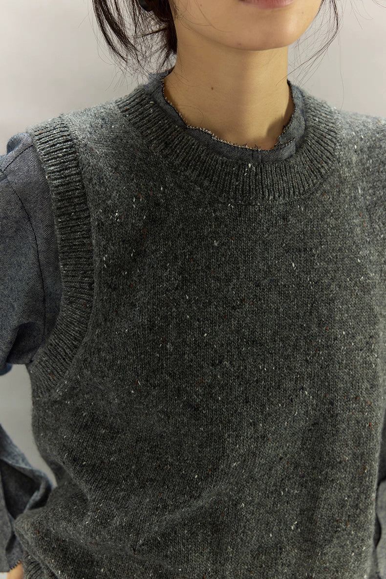 Close-up of speckled knit vest showing heather texture and ribbed neckline.