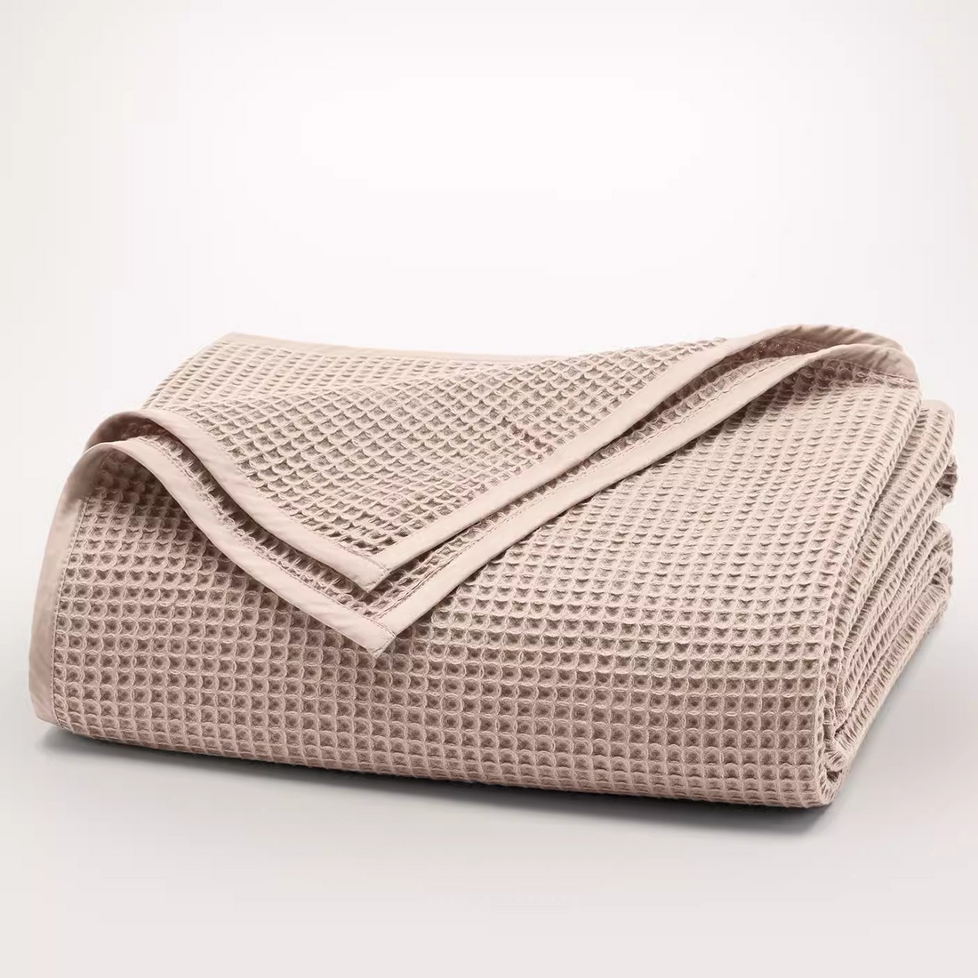 Folded light pink waffle gauze cotton blanket showing breathable textured fabric and clean stitched edges.