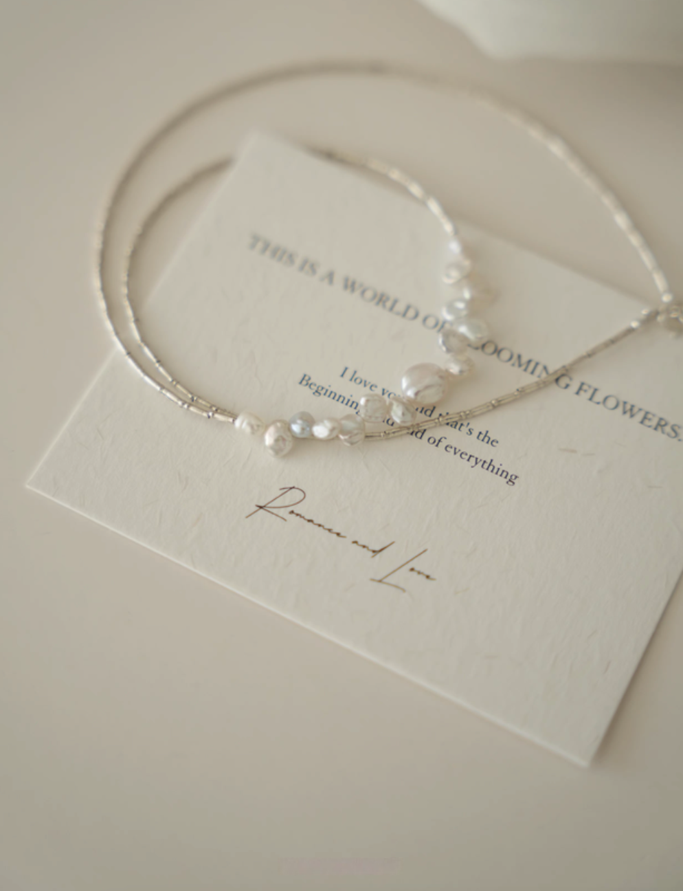 Soft white baroque pearl silver choker displayed on card flat lay highlighting elegant pearl arrangement