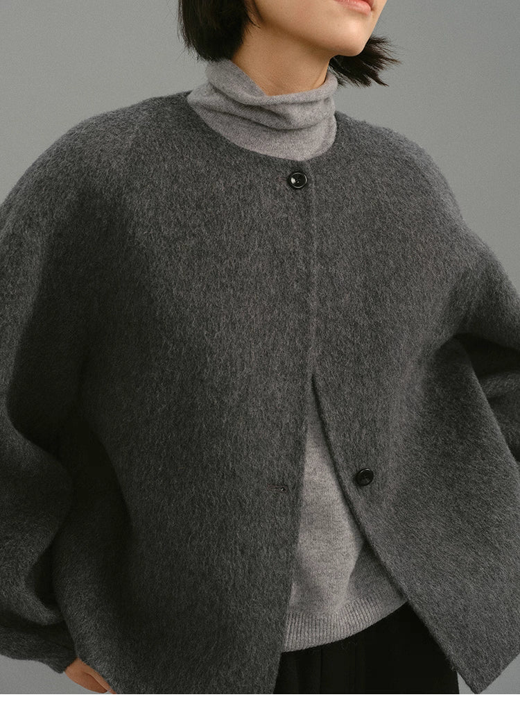 Close-up of charcoal cocoon jacket showing round neck and button details