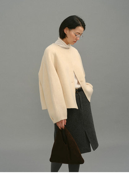 Side full-body view of cream cocoon jacket styled with grey skirt and brown bag