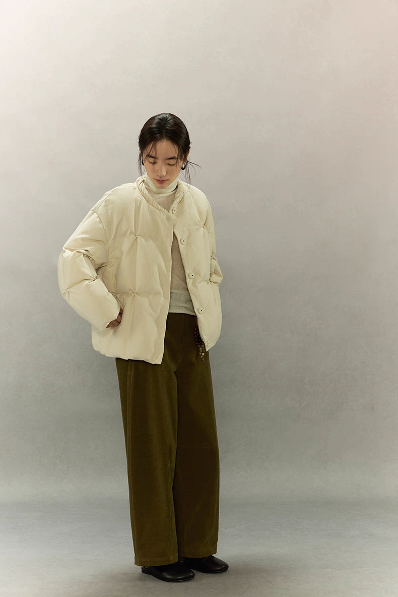 Model looking down in cream beige SoftCloud lightweight down jacket, hands in pockets, showing relaxed everyday styling.