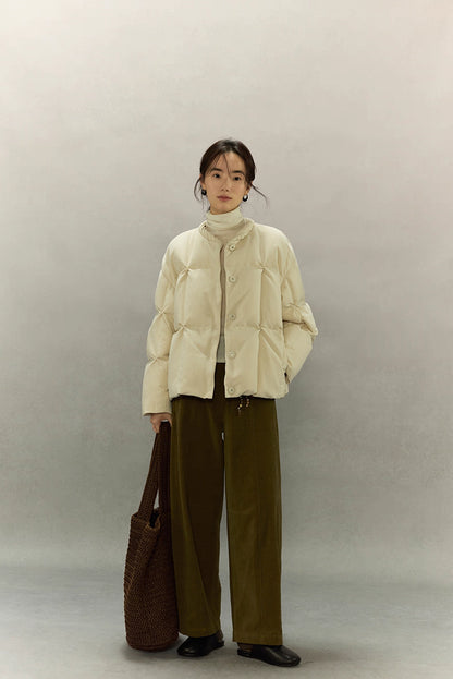 Full-body front view of model wearing cream beige SoftCloud down jacket with wide-leg olive pants and brown tote bag.