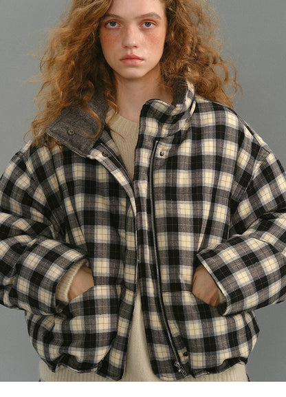 Close-up of the SoftGrid wool check puffer showing black and cream plaid, stand collar, and zipper front with hands in pockets.