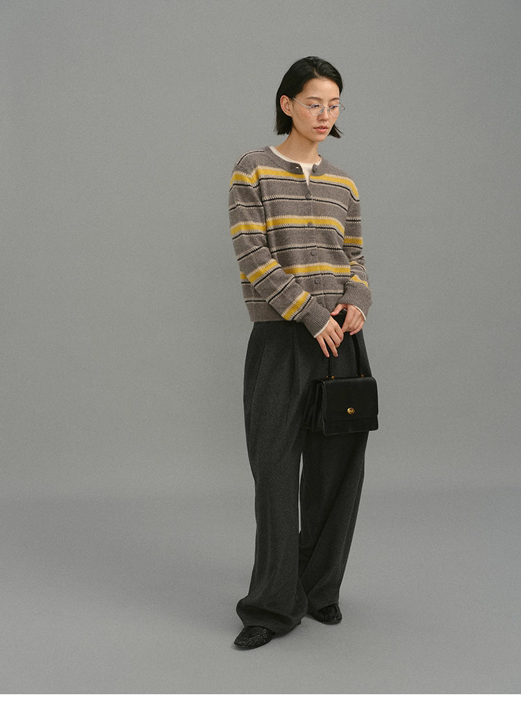Model wearing the taupe-yellow striped wool-blend cardigan with wide charcoal trousers, holding a black structured handbag against a grey backdrop.