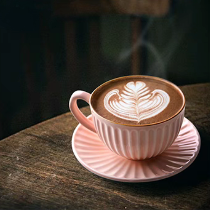 Pink striped ceramic cappuccino cup and saucer with latte art placed on wooden surface in cozy lifestyle scene