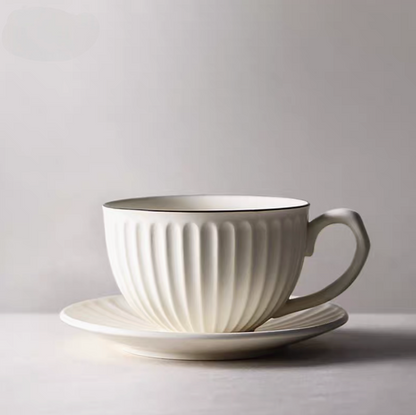 Side view of white striped ceramic cappuccino cup with saucer showing curved handle and vertical stripe detailing