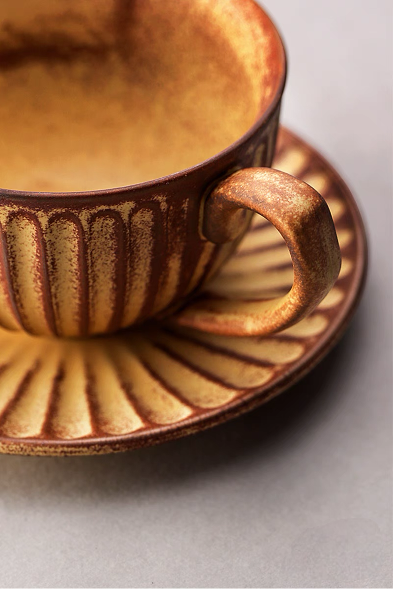 Close-up of yellow striped ceramic cappuccino cup handle and saucer showing textured glaze and handcrafted detail