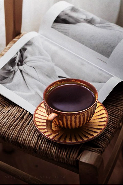 Yellow striped ceramic cappuccino cup filled with coffee placed on woven chair with magazine creating relaxed lifestyle scene