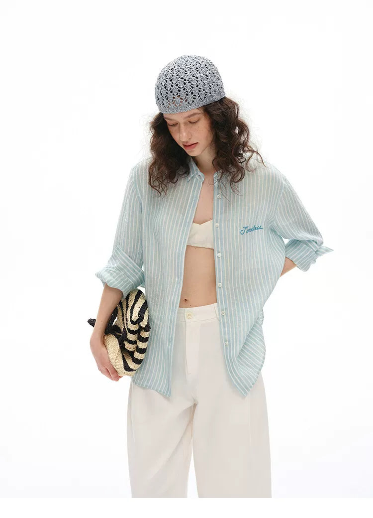 Woman wearing blue striped linen shirt with cream wide-leg pants, front view