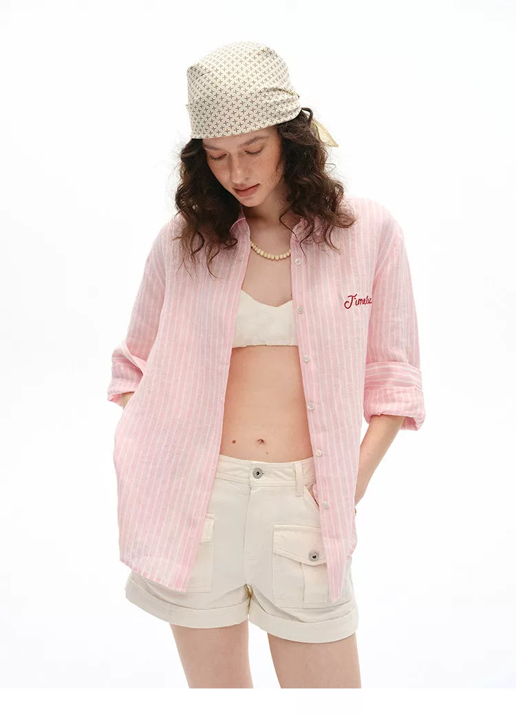 Woman wearing pink striped linen shirt with cream cargo shorts, front view