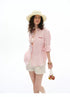 Pink striped linen shirt styled with woven bag and straw hat, front view