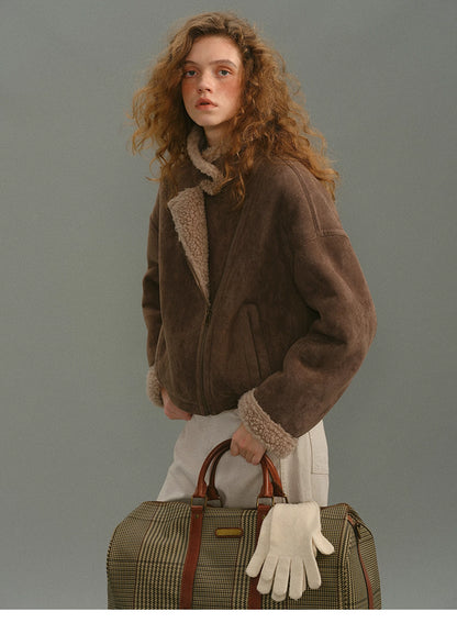 Mocha shearling jacket styled with plaid travel bag and white gloves.