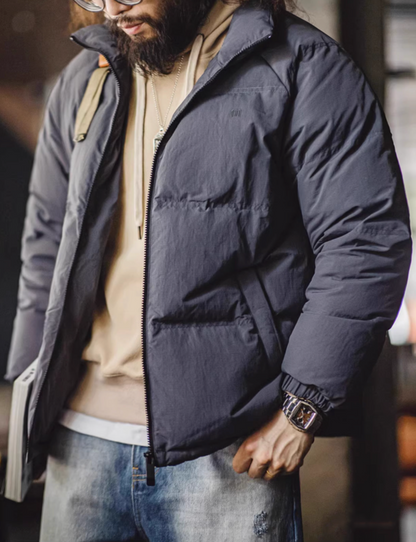 Dark gray SummitShield down jacket worn with hoodie and denim, featuring water-repellent shell and clean modern silhouette