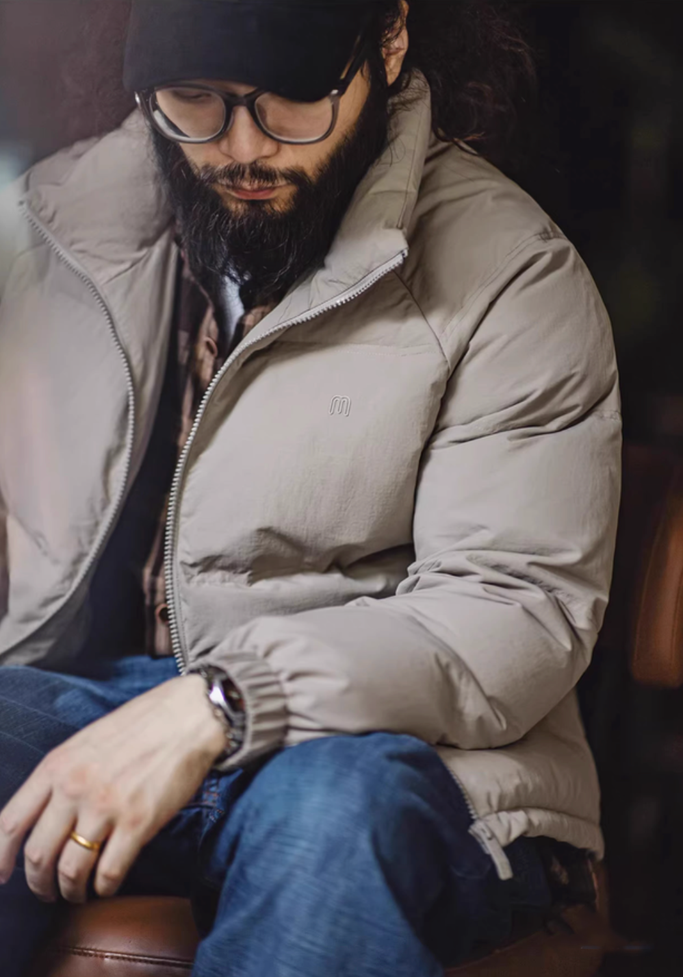 Close-up of light gray SummitShield down jacket showing matte texture, insulated padding, and relaxed fit while seated indoors