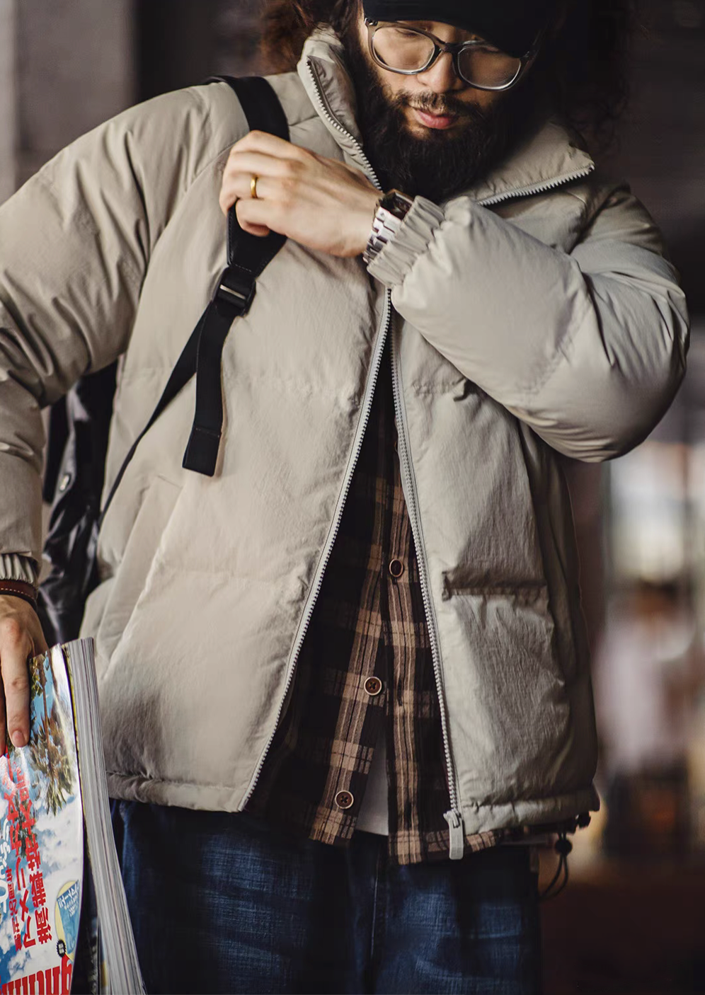 Front view of light gray SummitShield down jacket styled with plaid shirt and backpack, highlighting zip closure and everyday functionality