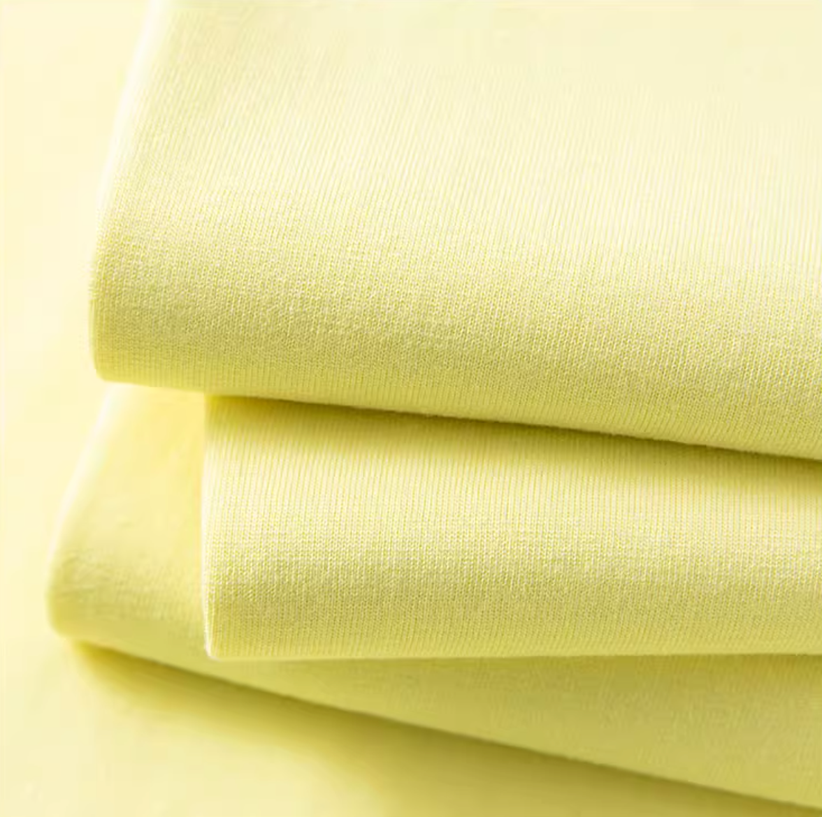 Folded lemon yellow cotton tee fabric close-up highlighting soft lightweight texture
