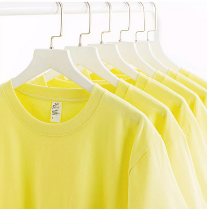Multiple lemon yellow cotton tees hanging on rack showing consistent color and fit