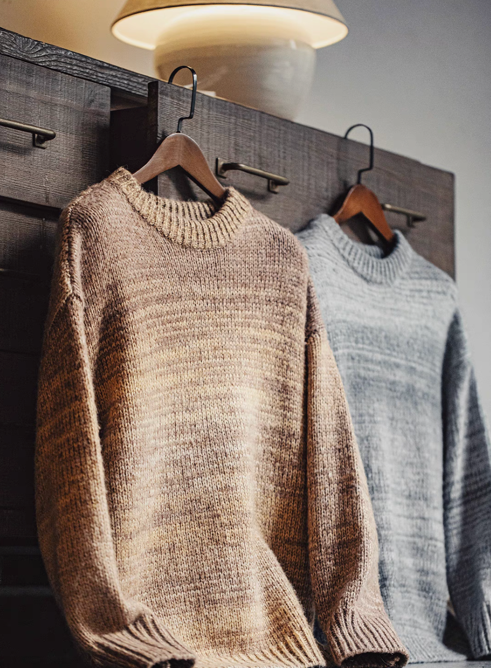 Sunset Drift Knit Sweater in Tea Brown and Lead Grey hanging on wooden rack showcasing gradient ombré knit texture crewneck design and relaxed fit