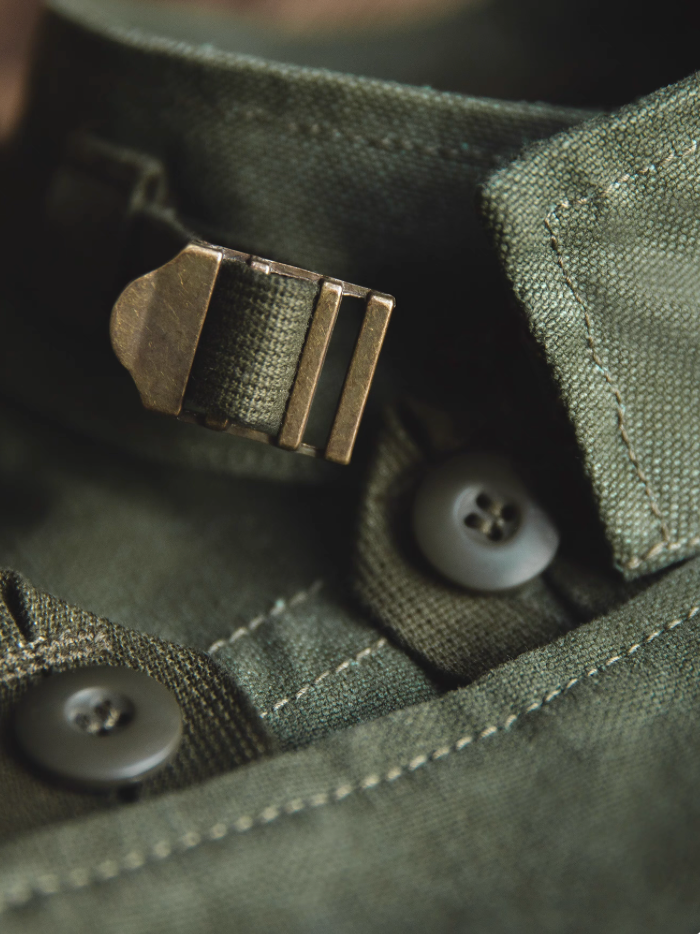 Close-up of collar and brass buckle detail on Swedish military motorcycle jacket – rugged green canvas.