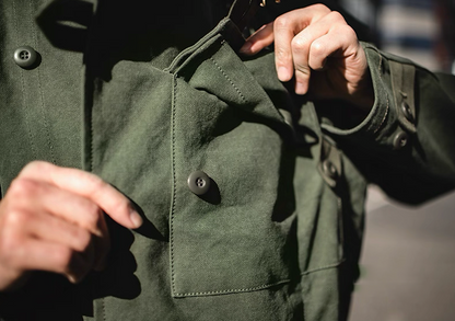 Model using chest pocket of Swedish military motorcycle jacket – functional workwear design.