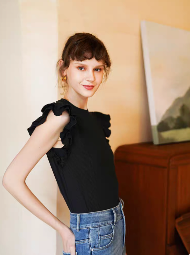 Black sleeveless ruffle top side angle on model showing slim fit silhouette and layered shoulder details