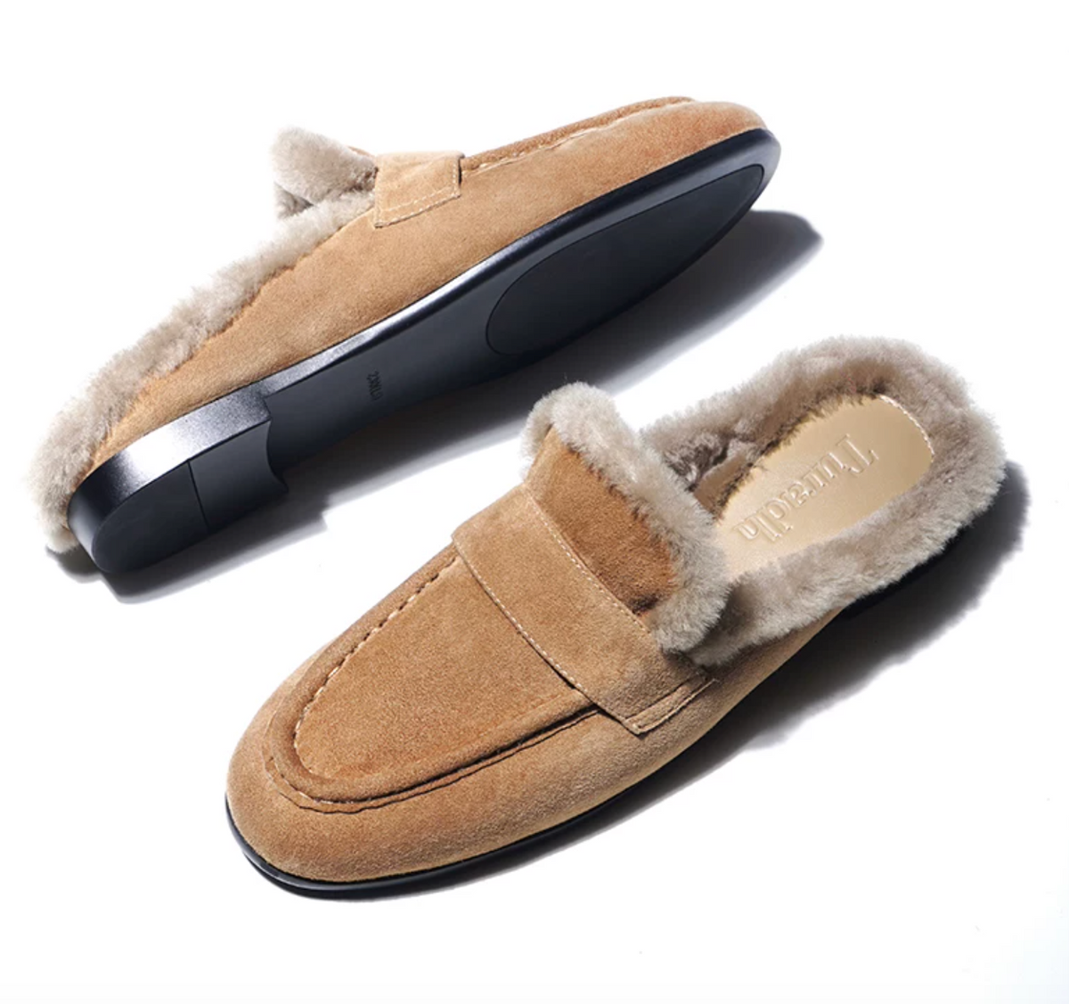 Tan shearling-lined mules showing the black non-slip rubber sole and low heel