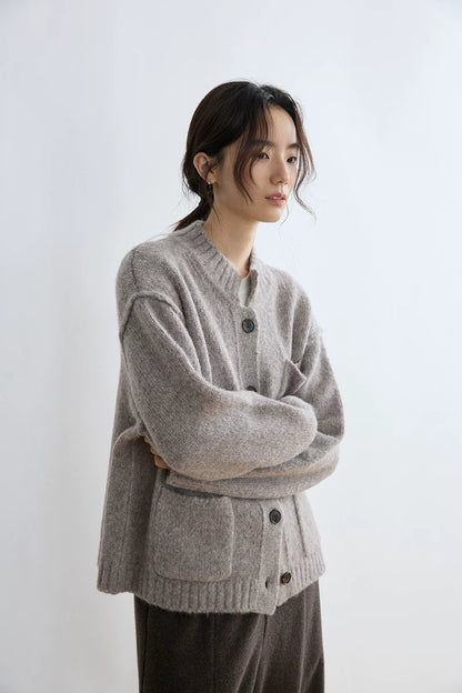 Taupe alpaca wool cardigan, front view with arms crossed showing sleeve and pocket