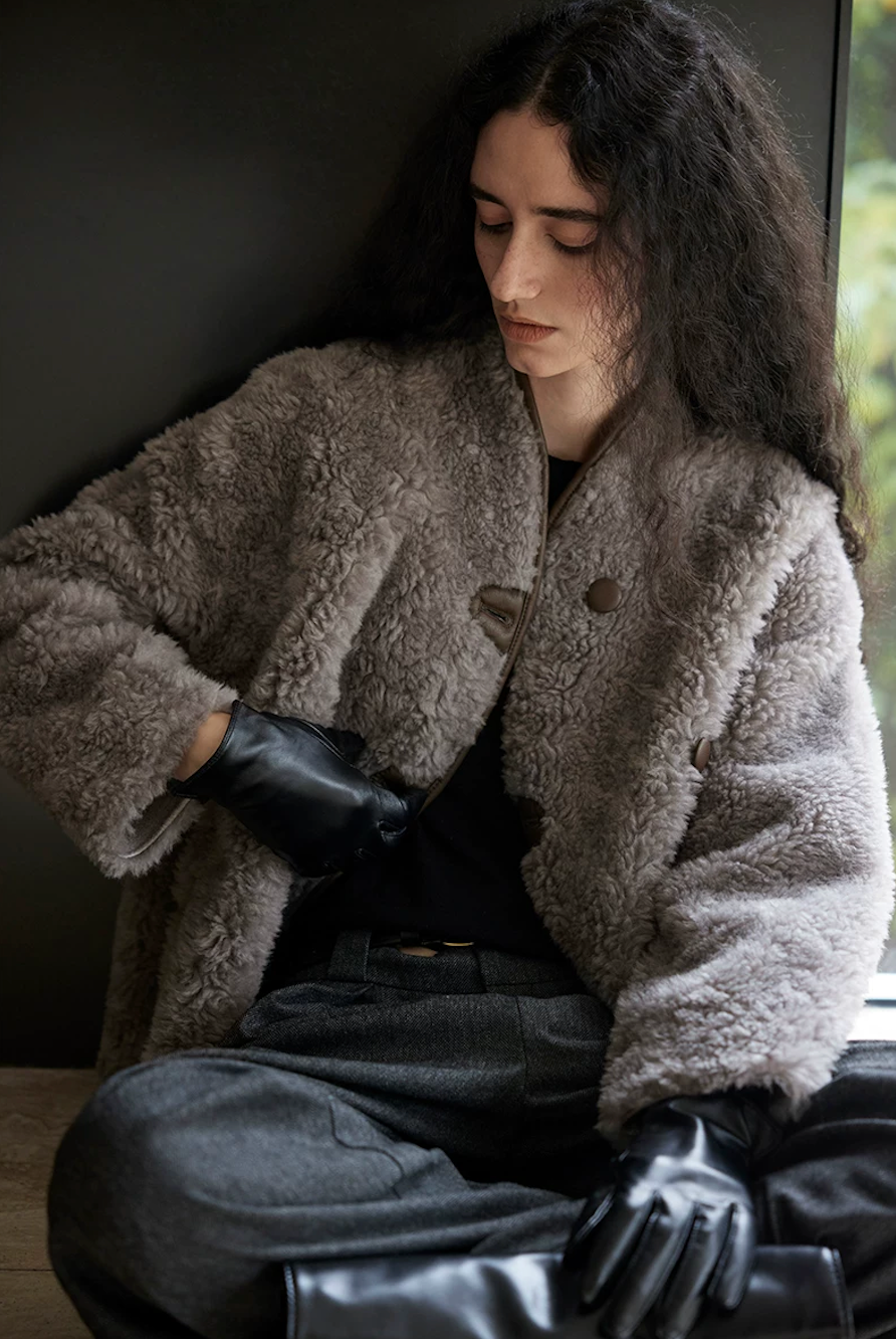 Seated view of a Taupe Gray curly wool jacket showing the brown buttons and piped neckline