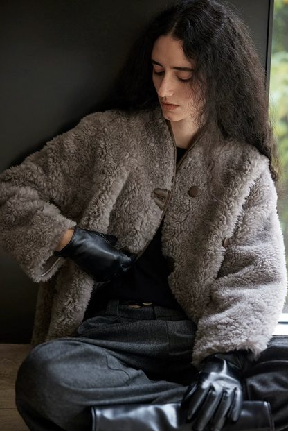 Seated view of a Taupe Gray curly wool jacket showing the brown buttons and piped neckline