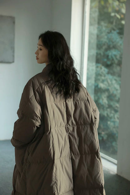 Back view of a Taupe A-line down coat showing square box quilting and raglan sleeves