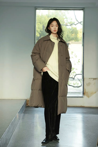 Taupe oversized long down coat worn open, showing the shirt collar and concealed placket