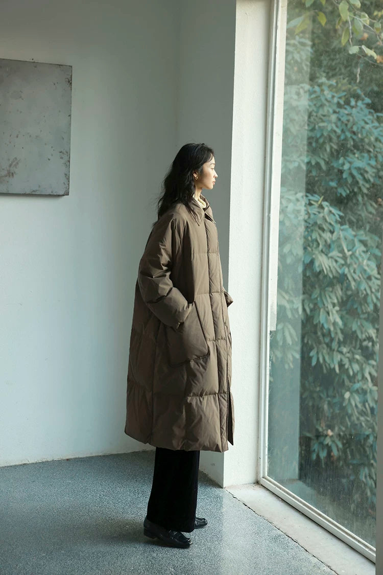 Side profile of a Taupe long down coat with point collar, square quilting, and patch pocket