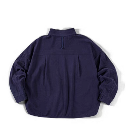 Blue textured cotton polo shirt flat lay back view showing curved hem, back pleat detail, and relaxed silhouette